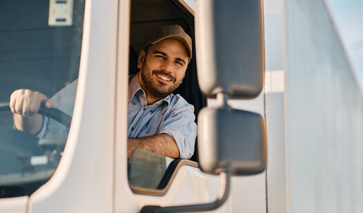 Mann mit Kappe sitzt in LKW und schaut aus dem Fenster des Führerhauses