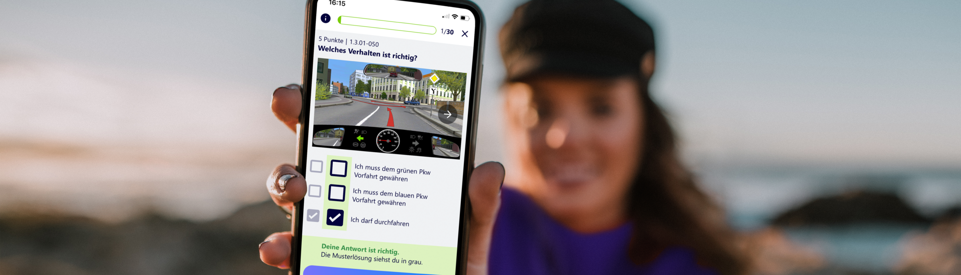 Junge Frau im Hintergrund hält Smartphone mit Führerschein Lern App nach vorne